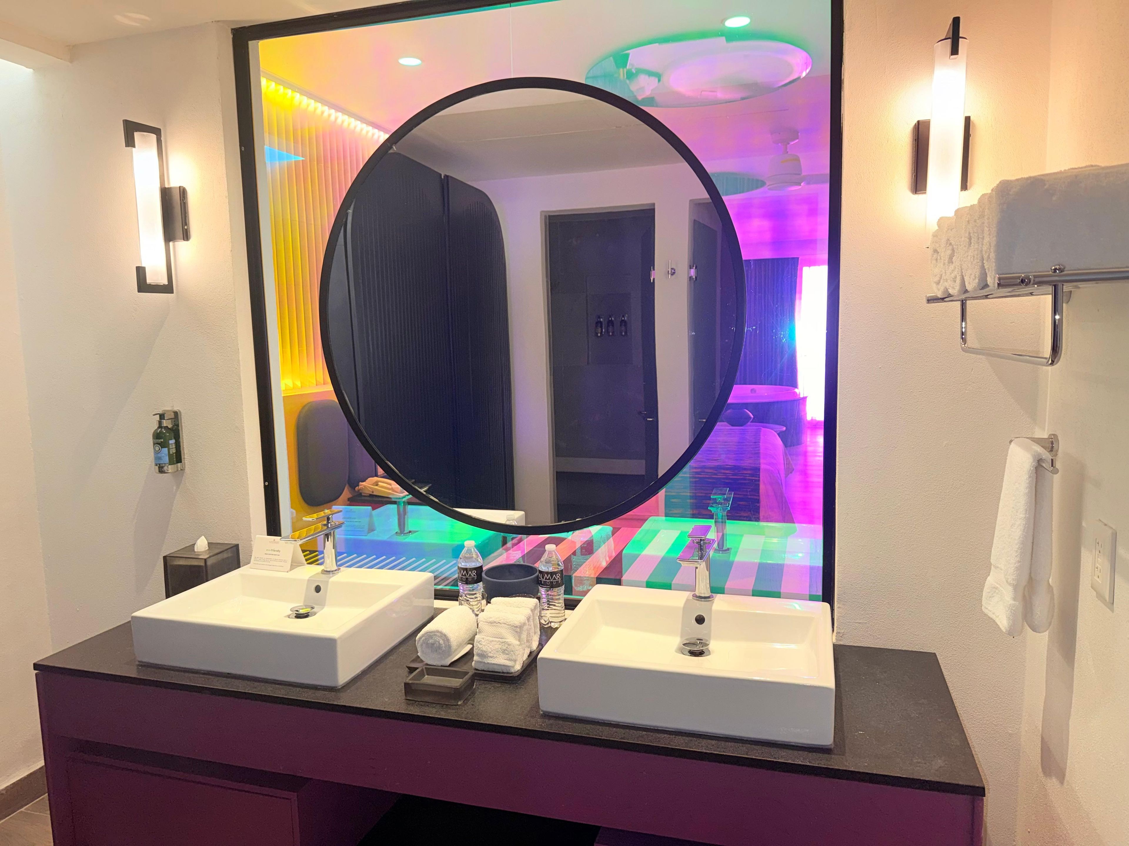 A bathroom with two sinks, a mirror, and a towel rack.