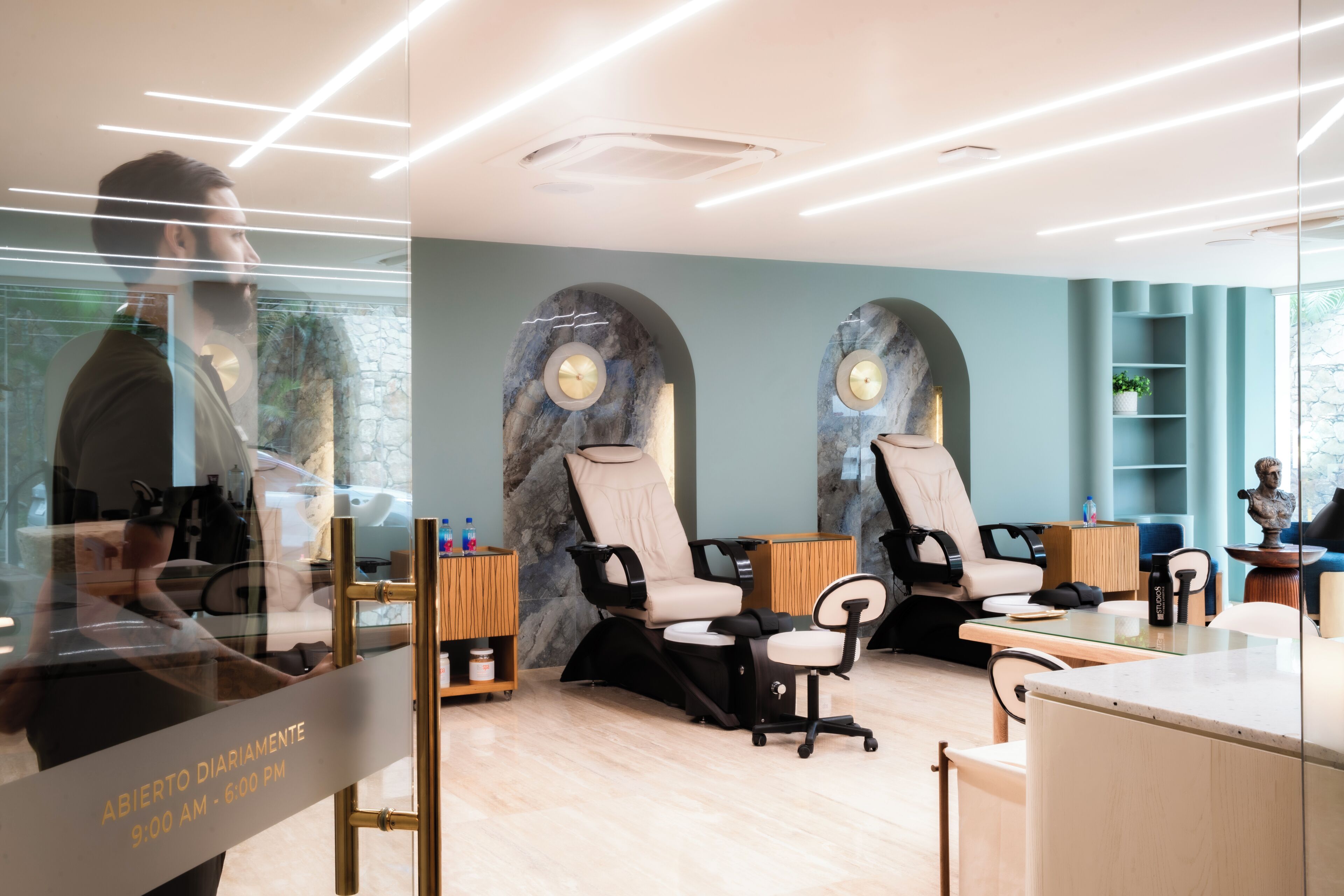 Een moderne spa met twee massagestoelen, een receptiebalie en een stenen muur.
