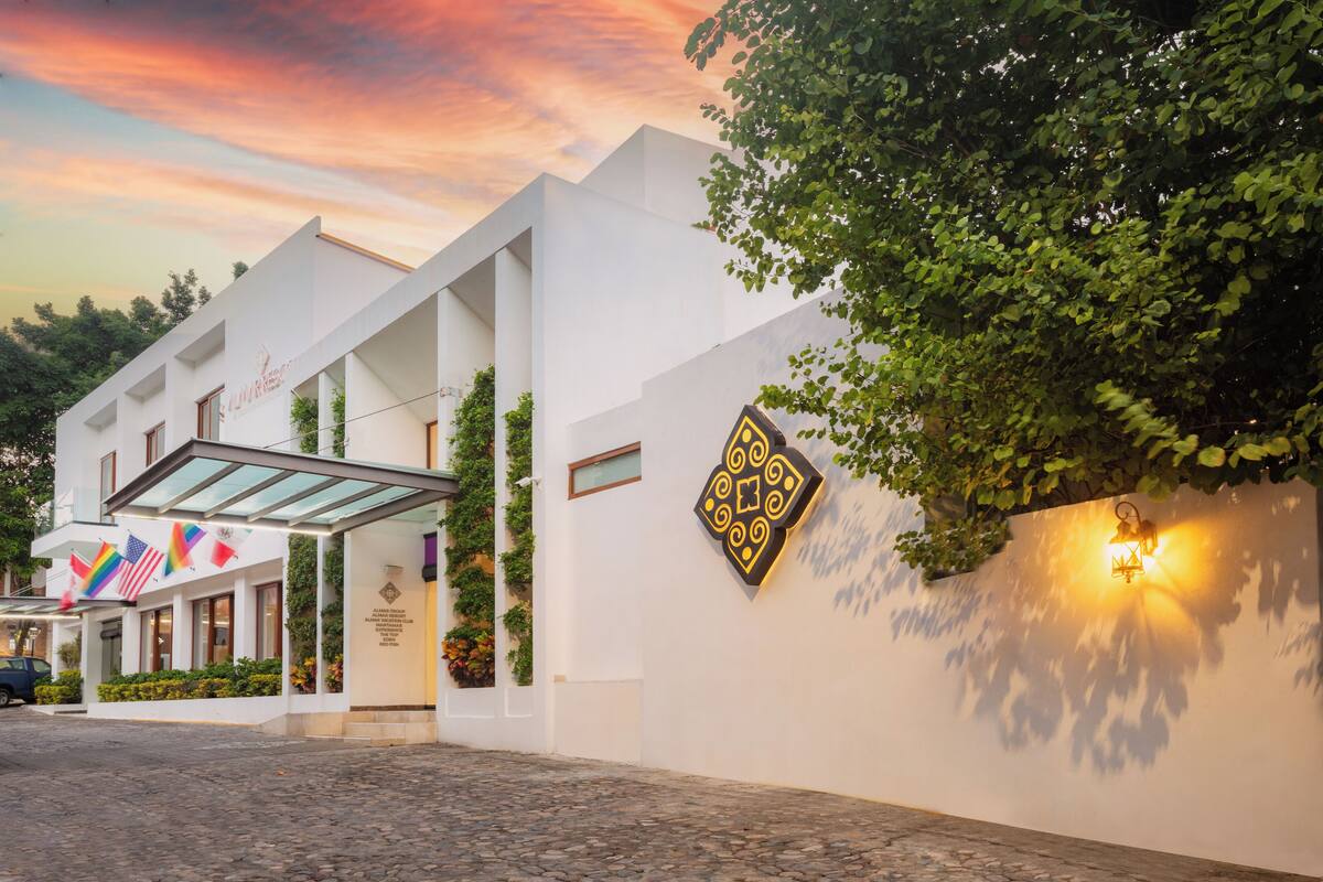 Un hotel moderno con fachada blanca, un acceso cubierto y un camino de entrada adoquinado.