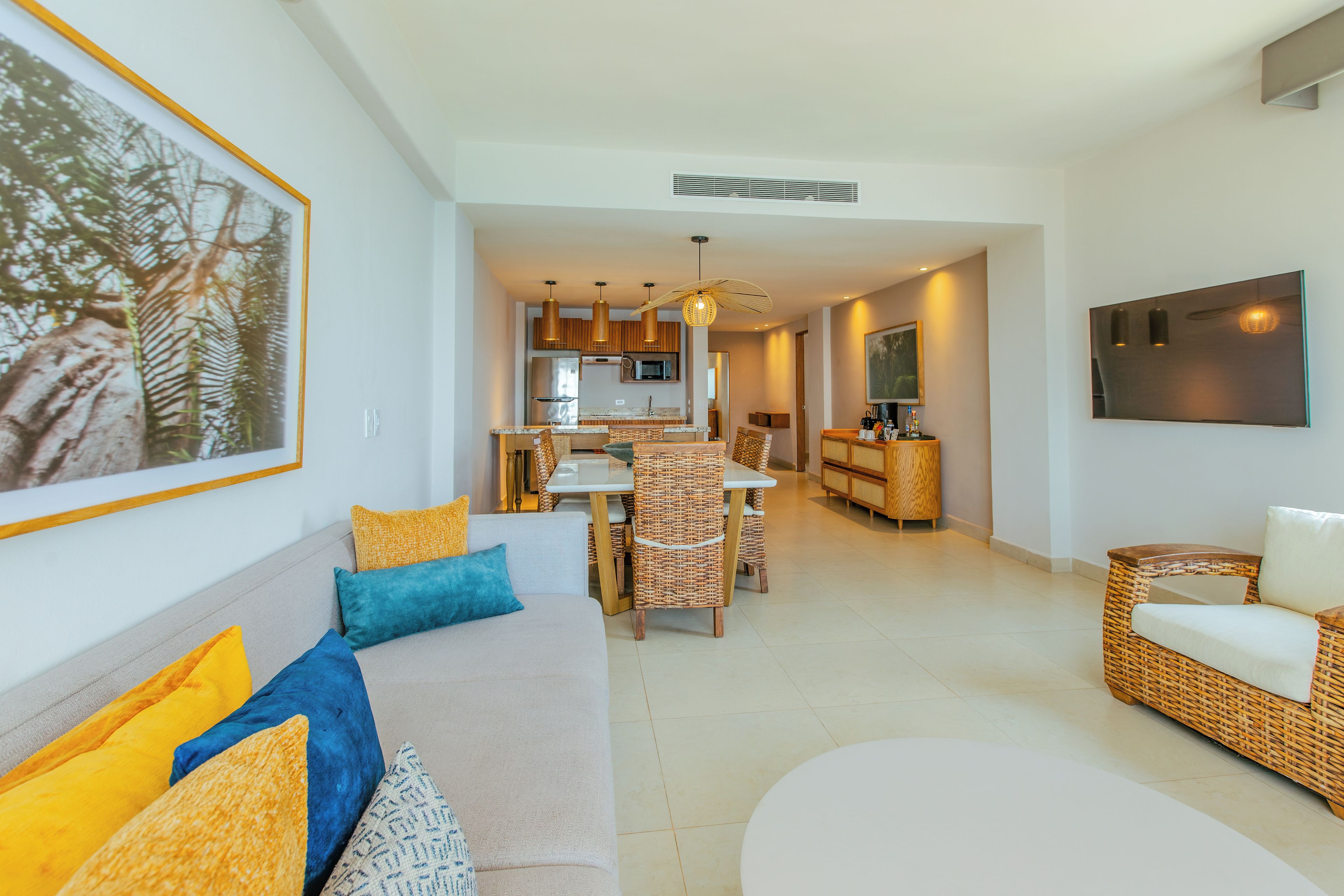 Una sala de estar moderna con sofá, comedor, cocina y un cuadro grande enmarcado en la pared.