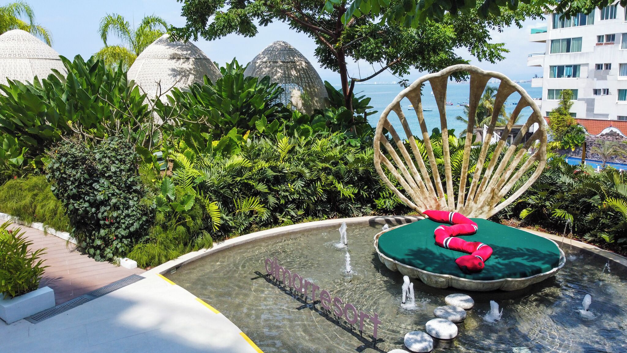 A pool area with a water feature, a chair, and lush greenery.