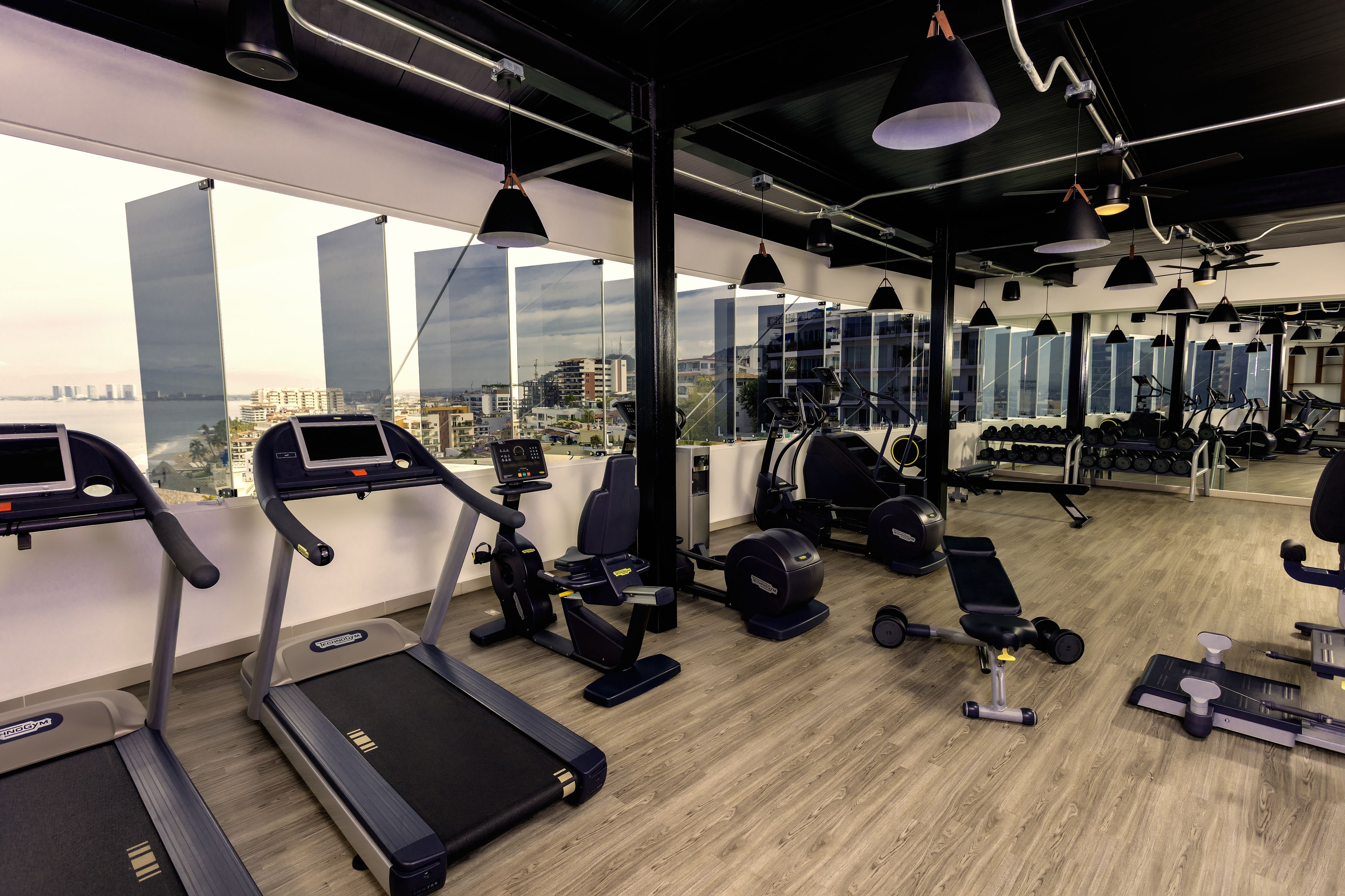 Un gimnasio con cintas de correr, elípticas y bancos de pesas.