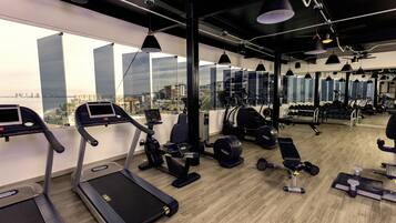 Un gimnasio con cintas de correr, elípticas y bancos de pesas.