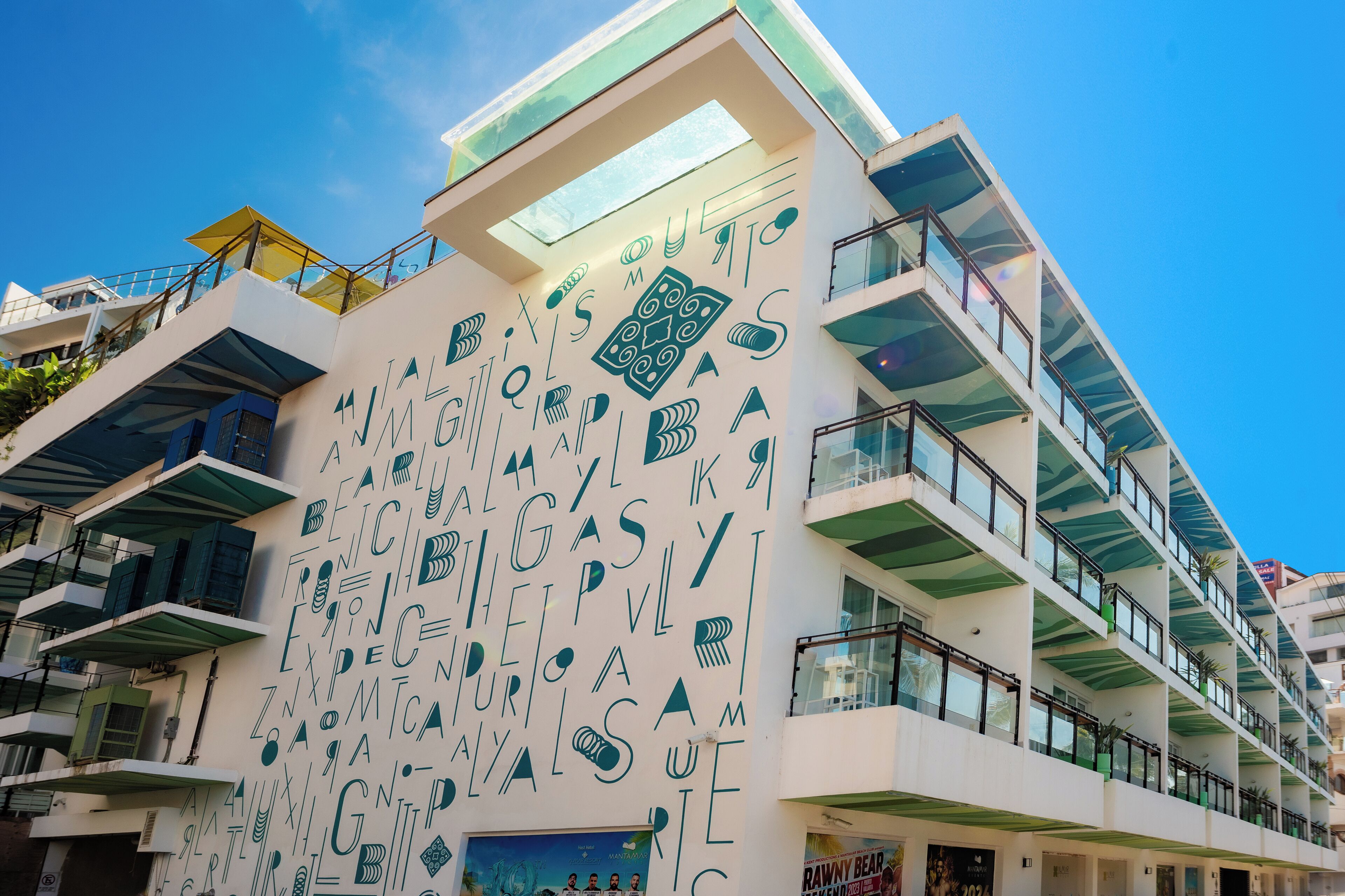 A modern building with multiple balconies and a unique facade featuring geometric patterns and text.