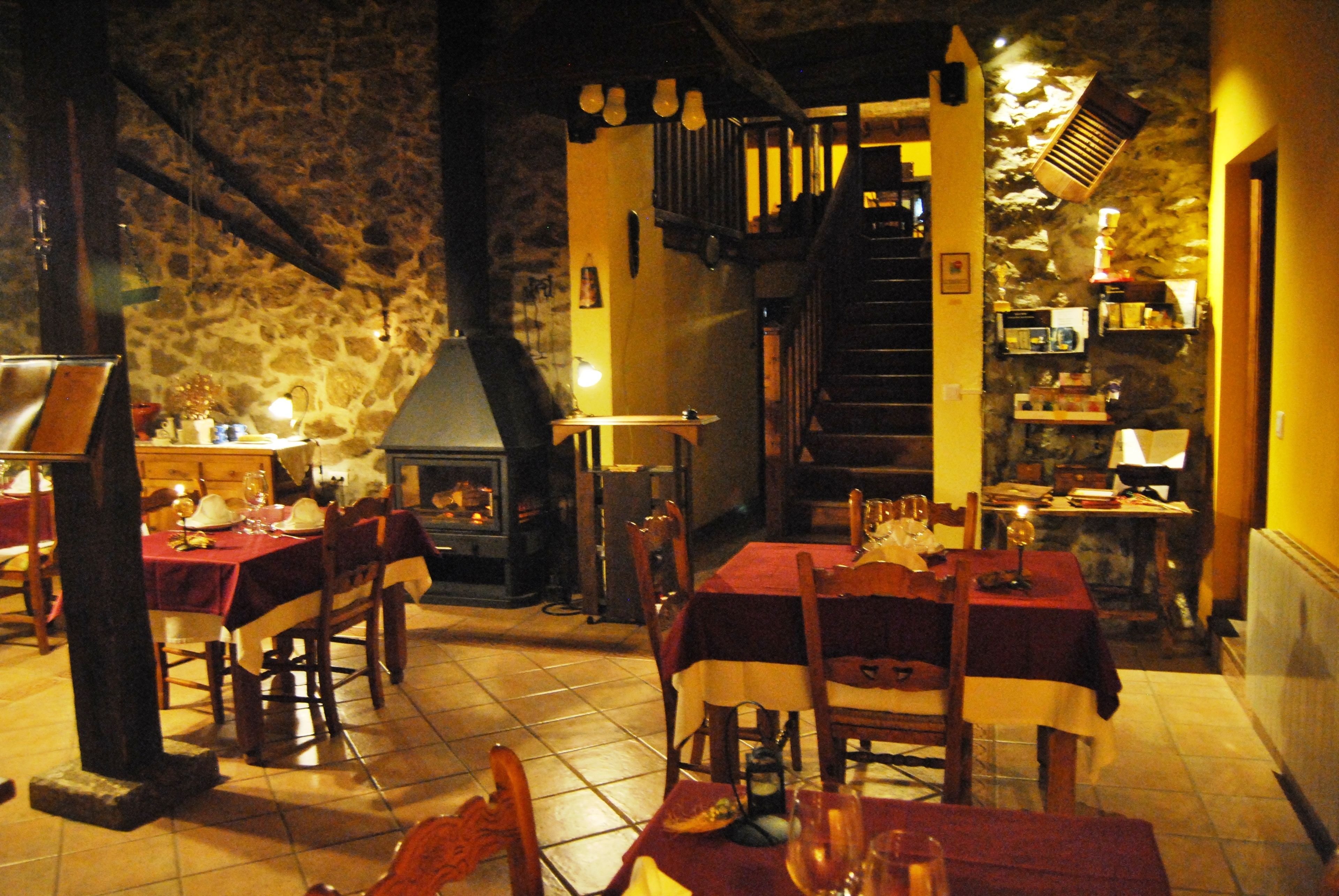 Een gezellig restaurant met stenen muren, houten tafels en een open haard.