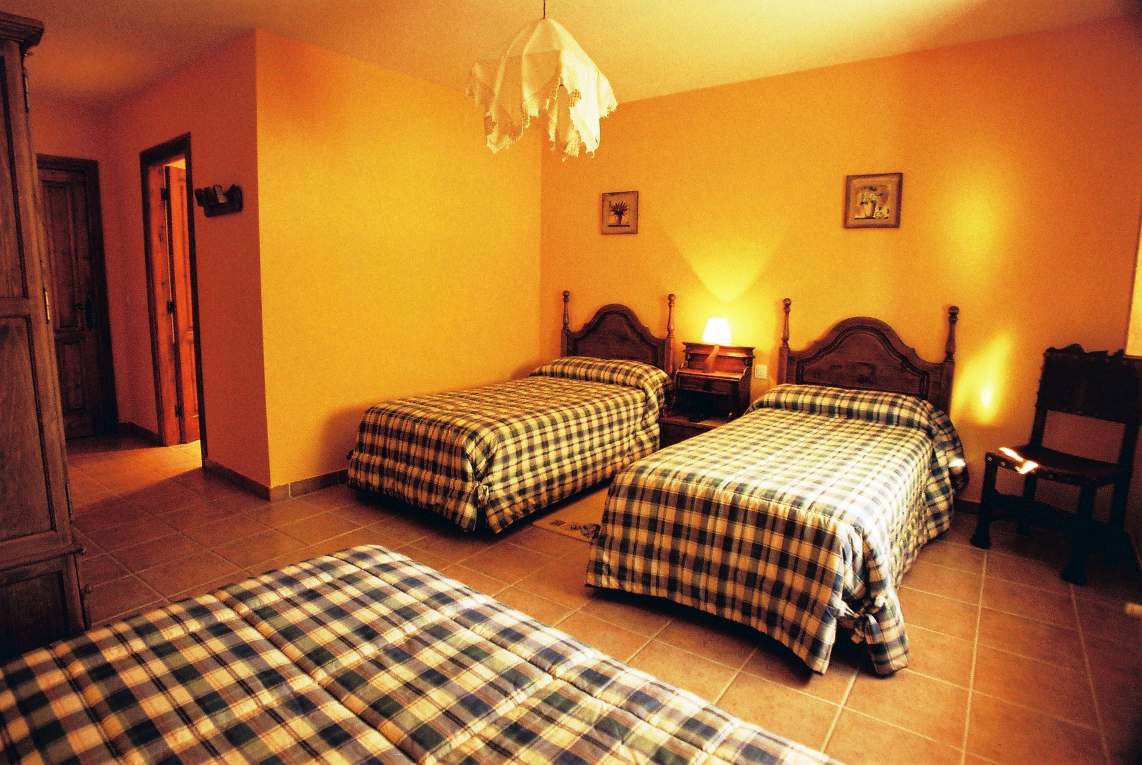 Una habitación con dos camas, un armario de madera y una silla.