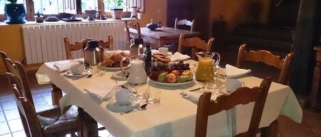 A dining area with a table set for breakfast, including croissants, fruit, and a pitcher of orange juice.