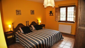 A bedroom with a bed, two bedside tables, a window with shutters, and a radiator. - La Trocha de Hoyorredondo (Hoyorredondo)