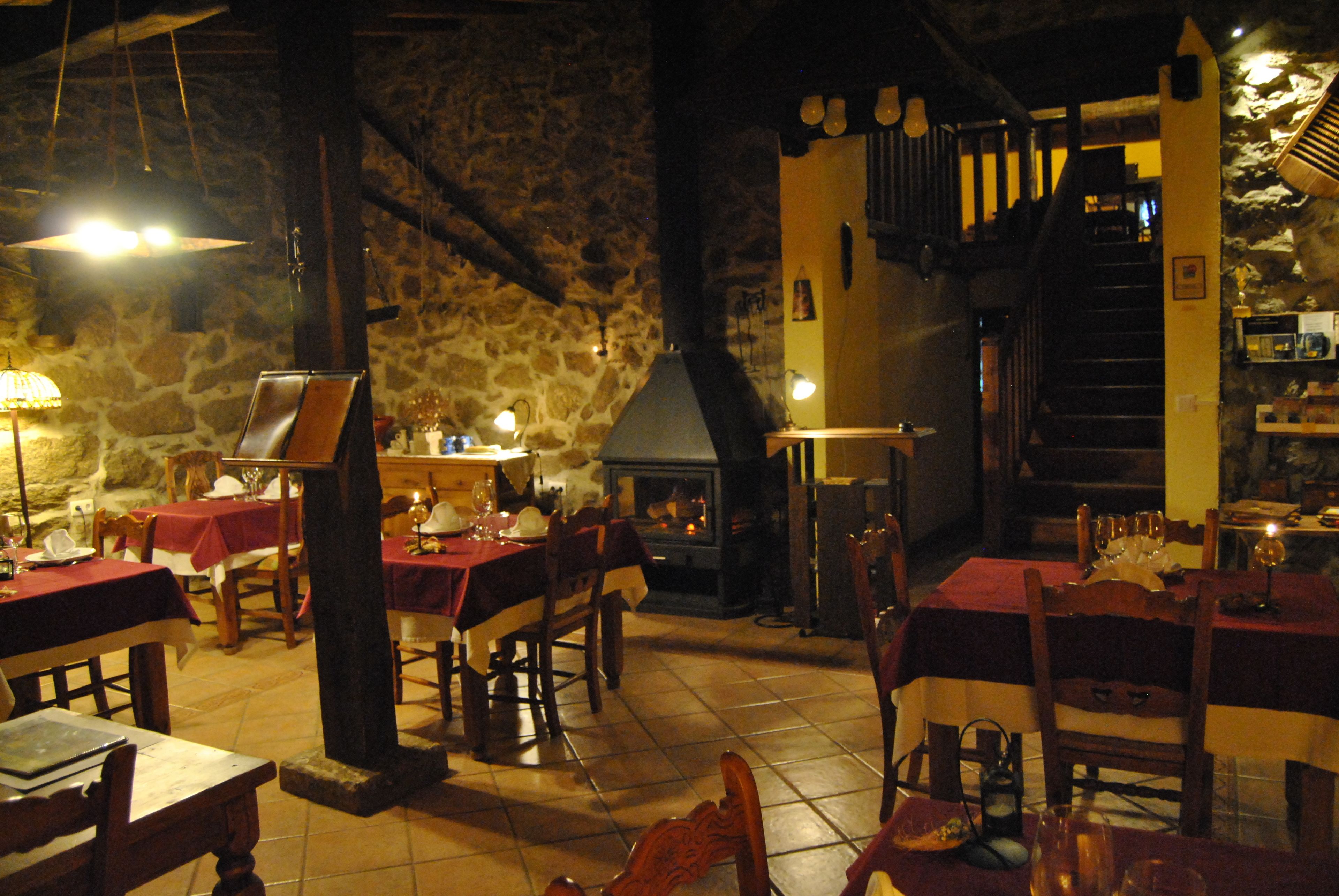 A restaurant with stone walls, wooden tables, and a fireplace.