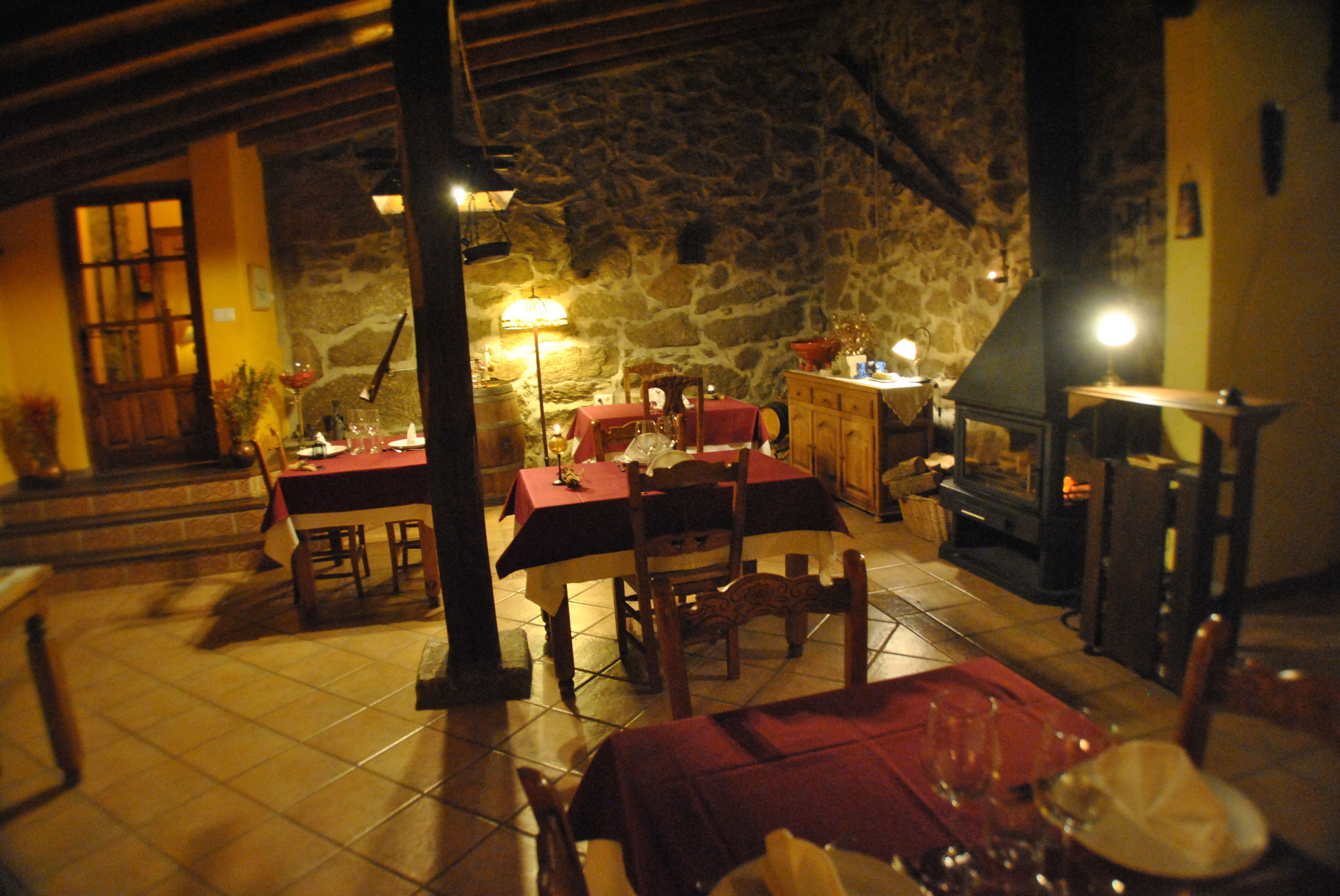 A cozy dining area with a stone wall, wooden furniture, and a fireplace.