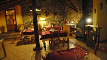 A cozy dining area with a stone wall, wooden furniture, and a fireplace.