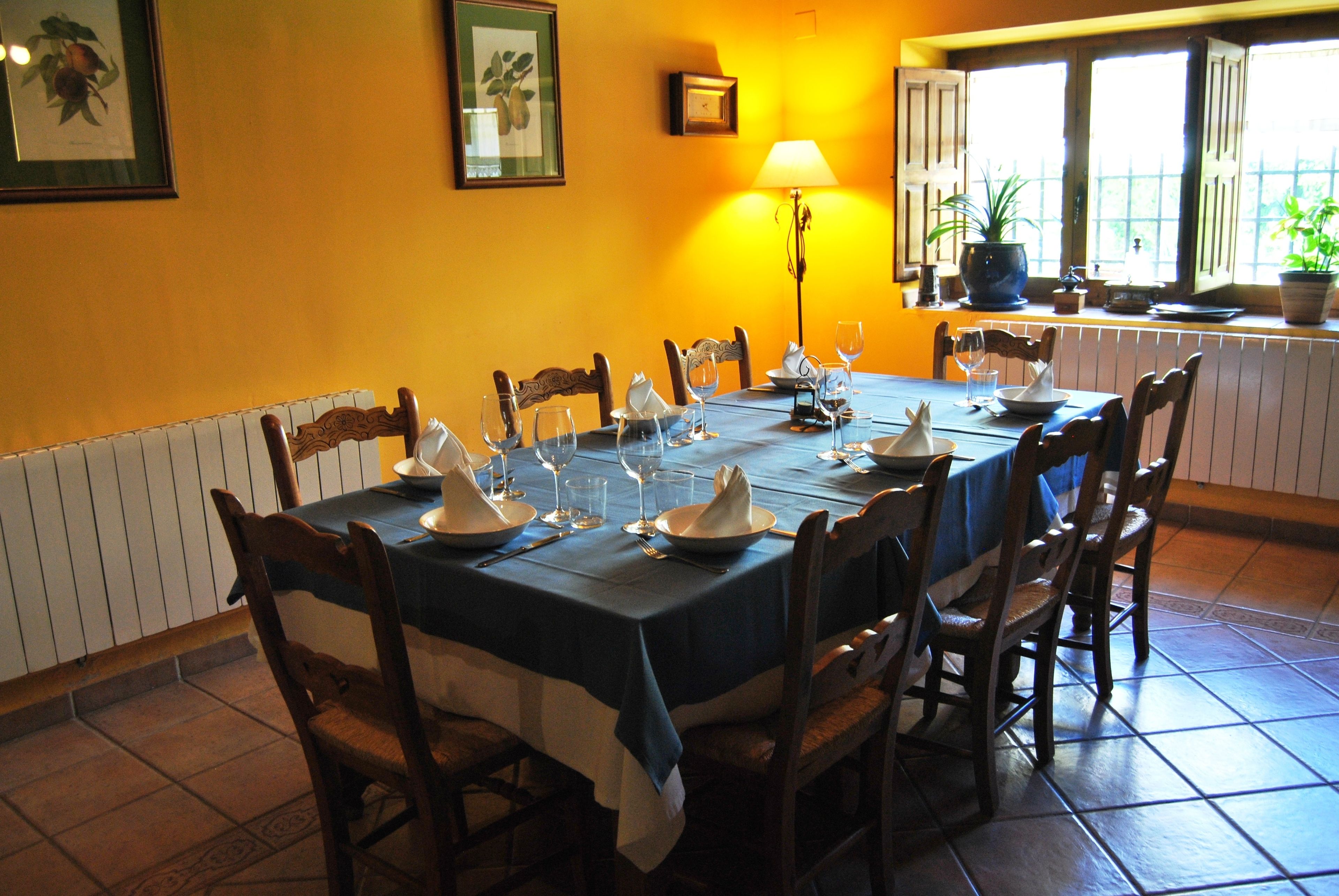 A dining room with a table set for six, surrounded by wooden chairs.