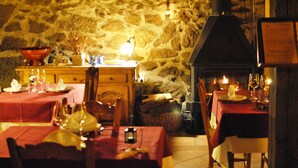 A cozy dining area with stone walls, wooden furniture, and tables set for a meal. - La Trocha de Hoyorredondo (Hoyorredondo)