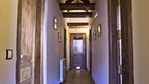 Un pasillo con puertas de madera, un radiador y cuadros en las paredes.