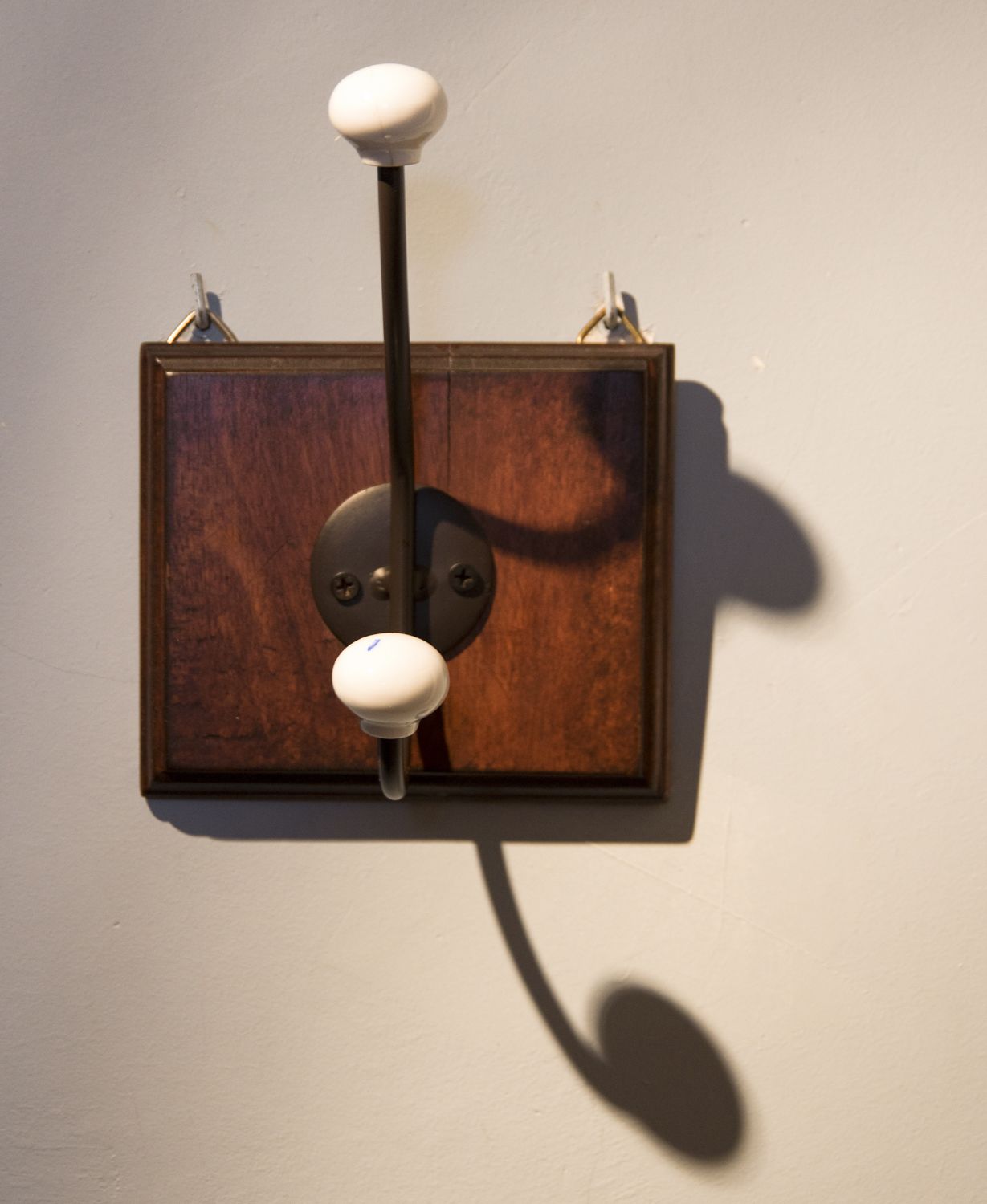 A wall-mounted light fixture with a wooden base and two spherical knobs.