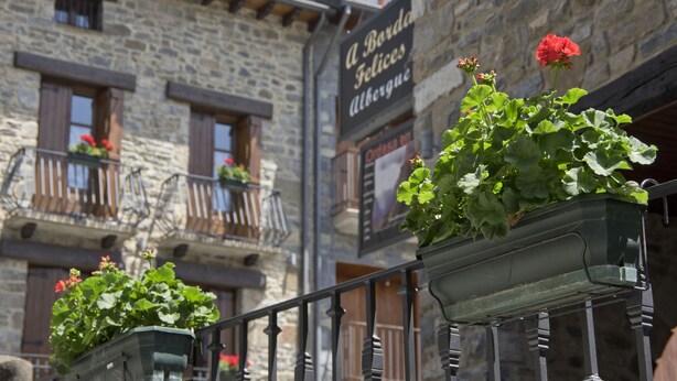 Un edificio de piedra con balcones y macetas con flores.