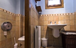 A bathroom with a toilet, a sink, a radiator, and a trash bin.