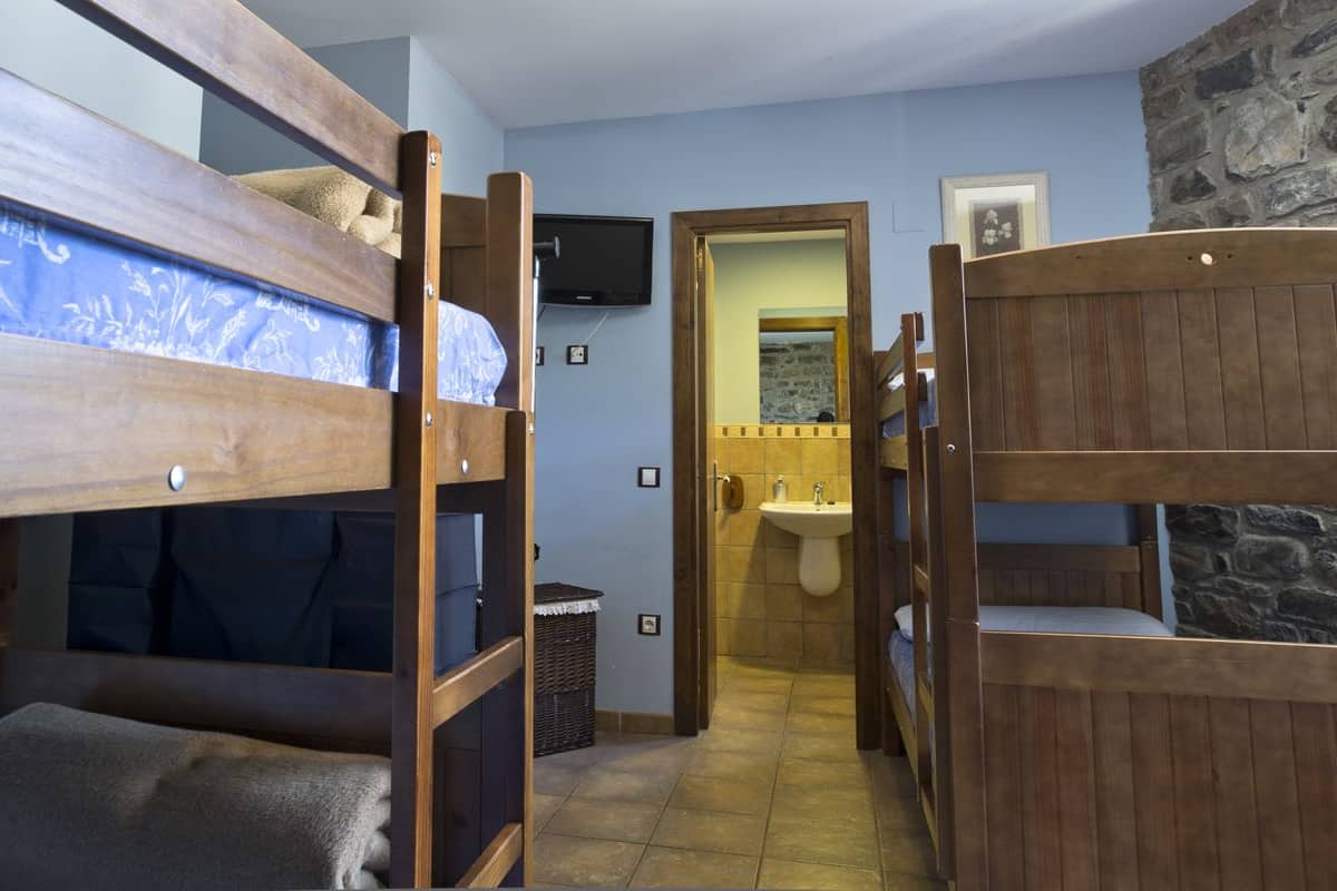 A bunk bed room with a bathroom visible through an open door.
