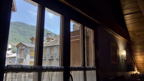 Una habitación con ventanas amplias, paredes de madera y vistas a un pueblo montañoso.