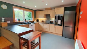 A modern kitchen with wooden cabinets, a stainless steel refrigerator, and a built-in oven. - Torcroft Lodges (Inverness)