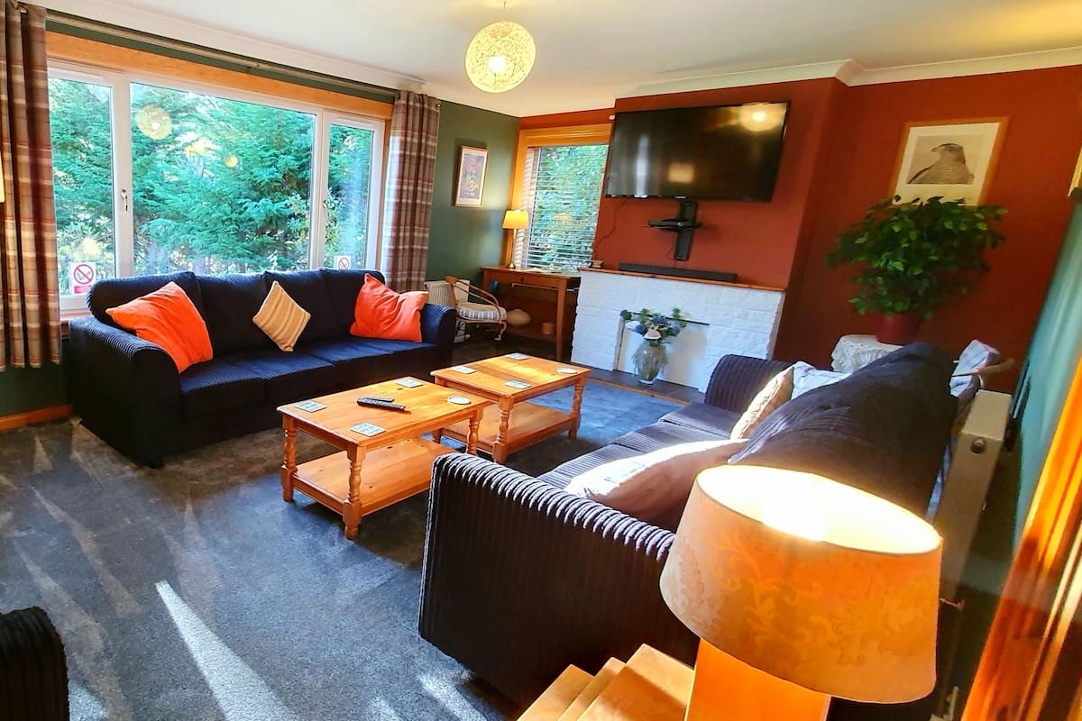 A living room with a sofa, armchairs, a coffee table, and a TV.