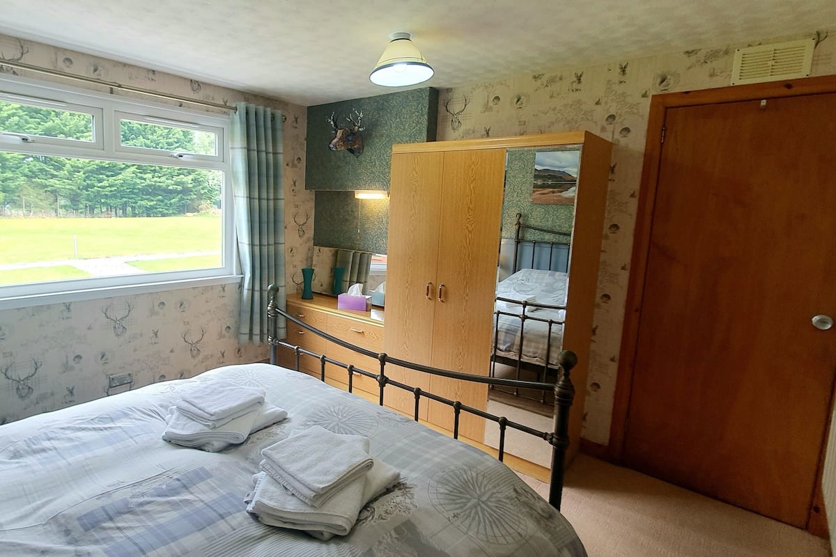 A bedroom with a bed, a wardrobe, a radiator, and a window with curtains.