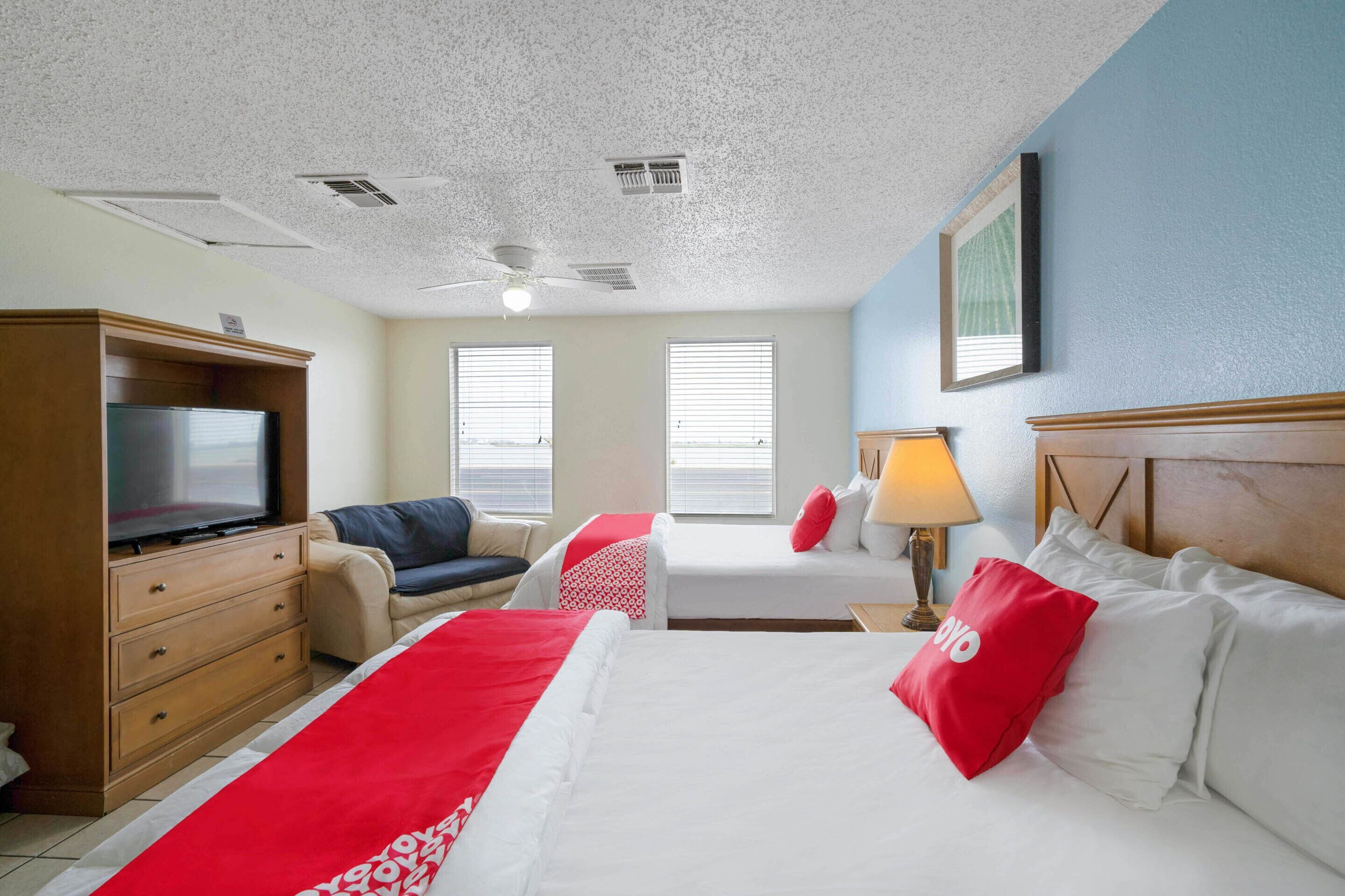 Una habitación de hotel con una cama, dos sofás, un televisor y un ventilador de techo.