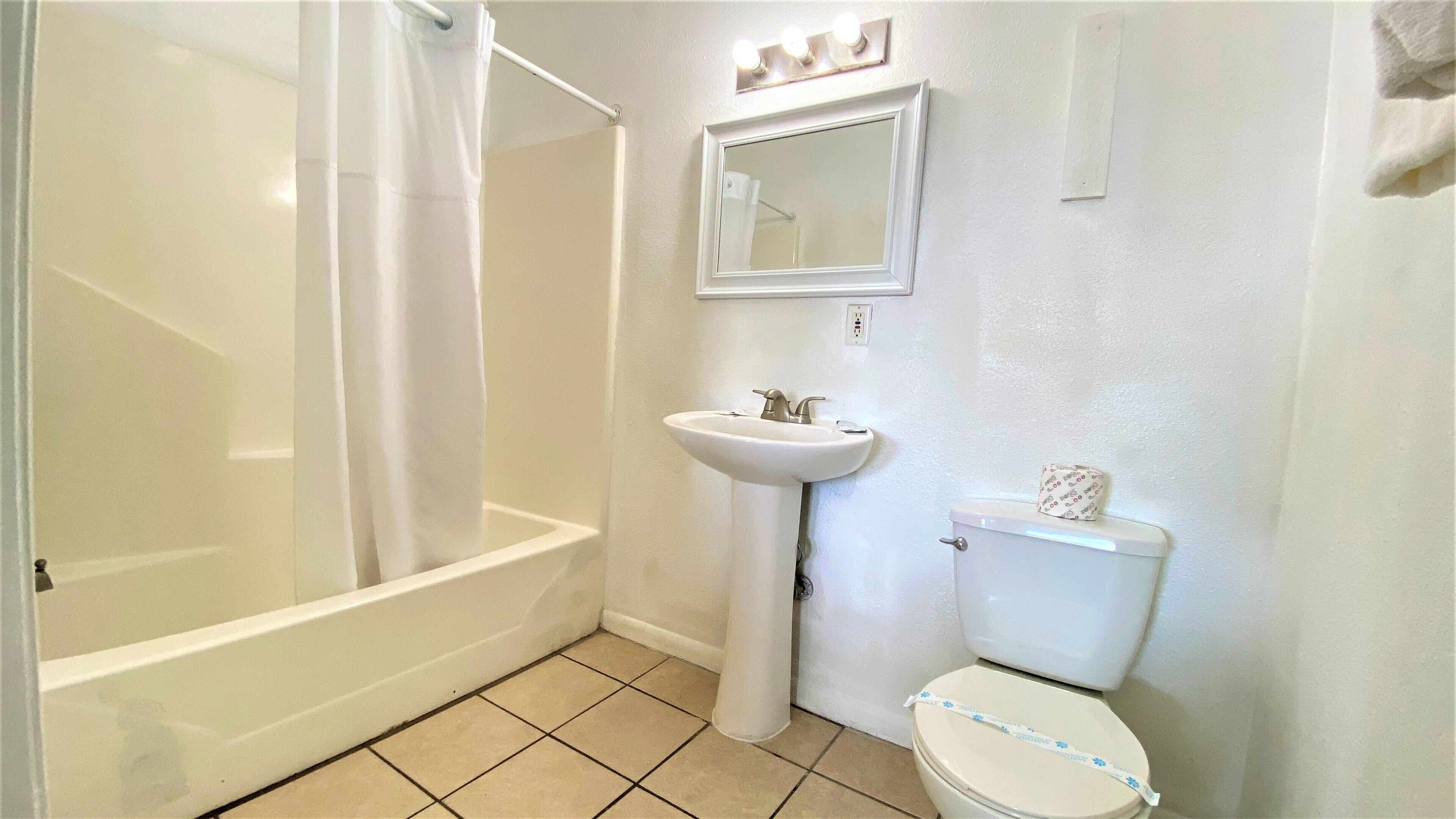 A bathroom with a shower, sink, and toilet.