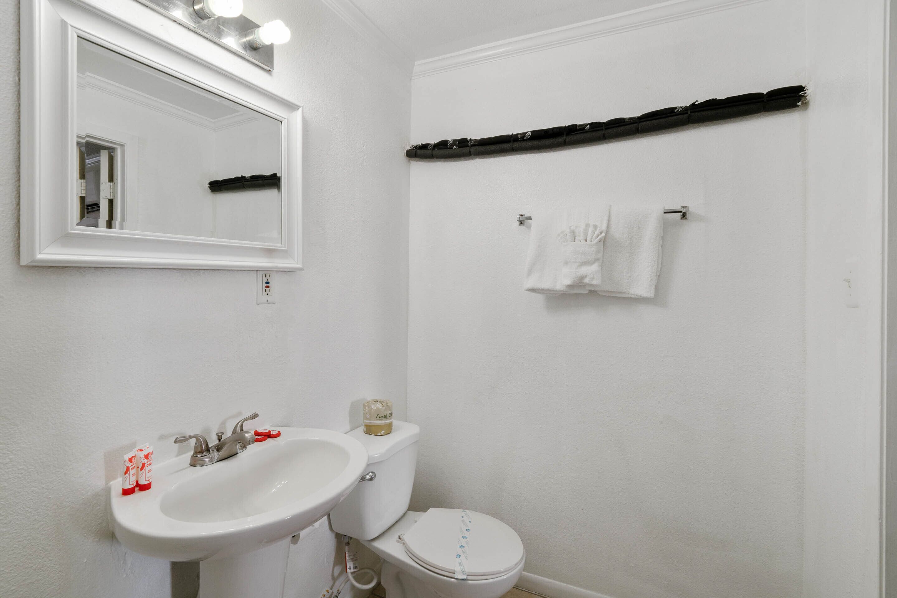 A bathroom with a white sink, a toilet, a mirror, and a towel rack.