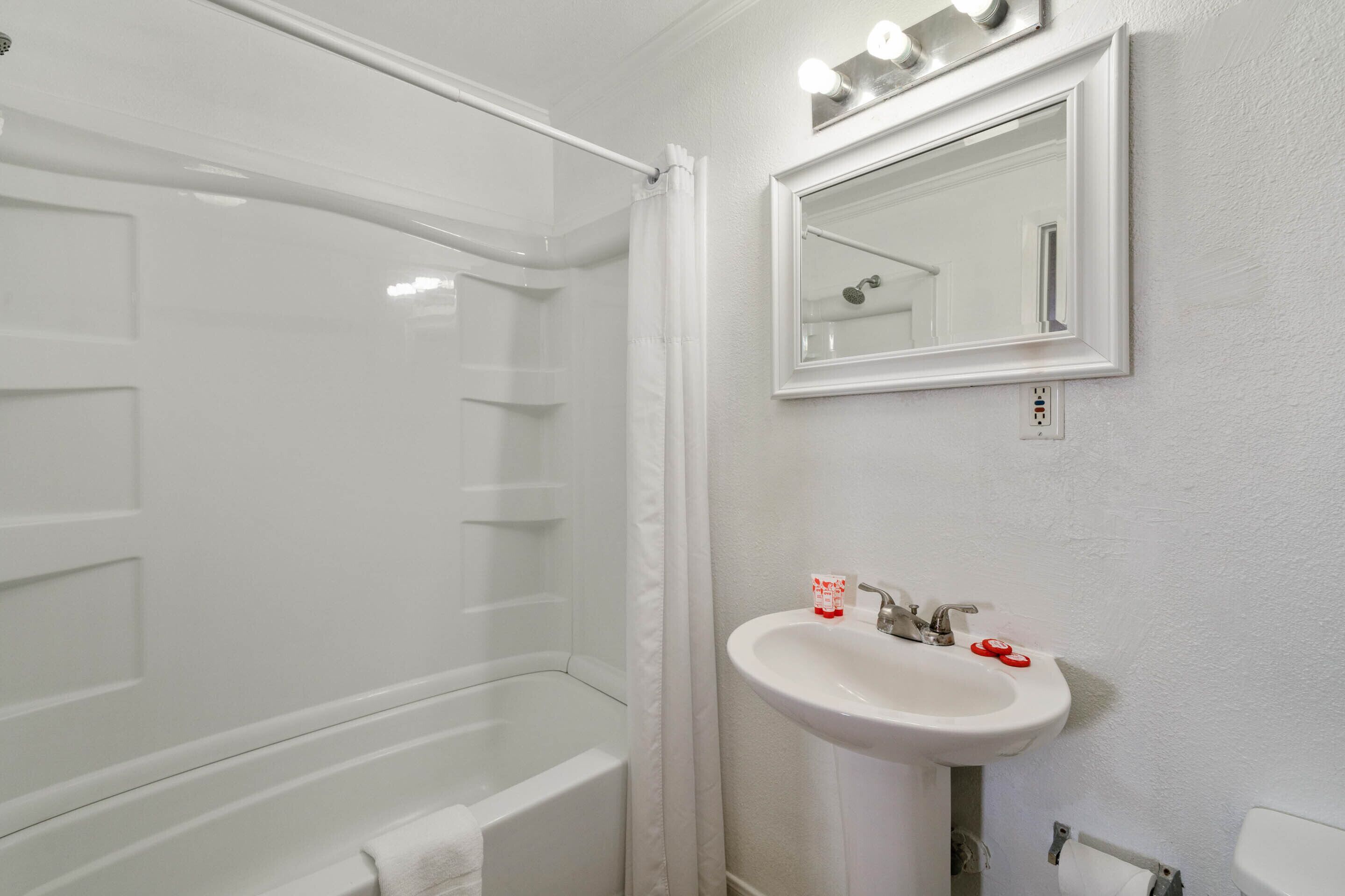 A bathroom with a bathtub, a sink, and a mirror.