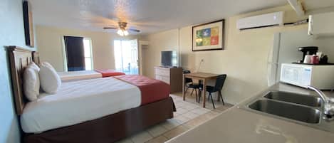 Habitación de hotel con cama, escritorio, silla, microondas y lavamanos.