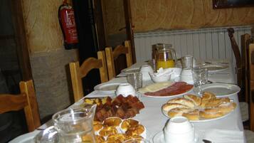 Een ontbijttafel gedekt met borden, glazen en diverse soorten eten.