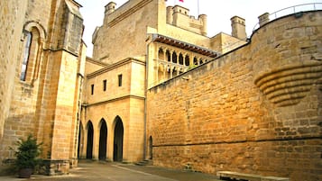 A historic stone building with arched doorways and a flag on top.