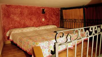 Quarto com uma cama, uma cadeira de madeira, estrutura de cama de metal, uma luminária na parede e uma cortina.