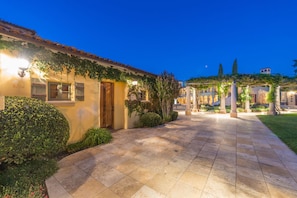 A building with a tiled pathway leading to a door, surrounded by greenery and a well-lit area. - CaliPaso Winery (Paso Robles)
