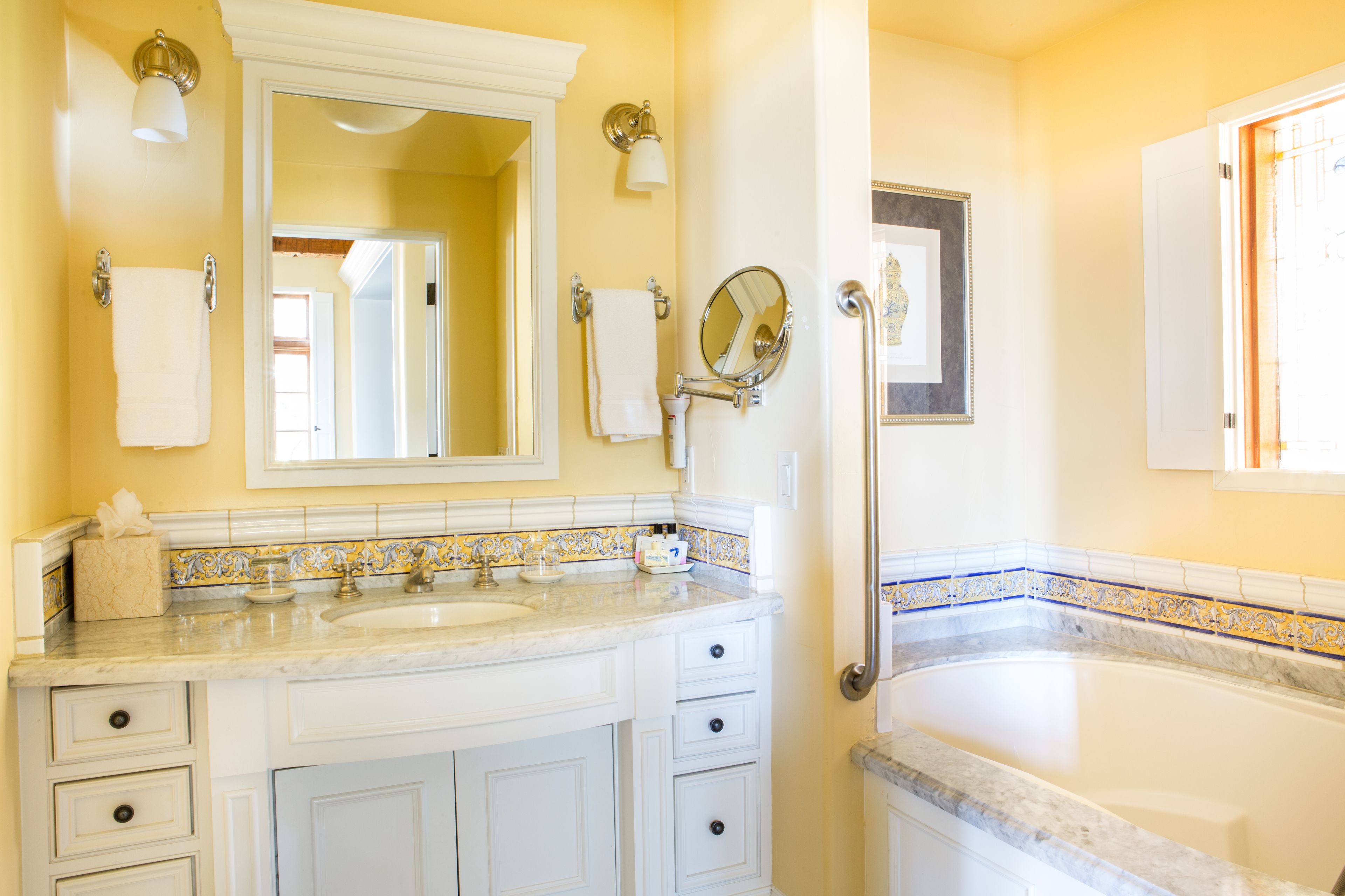 A bathroom with a large mirror, two sinks, a bathtub, and a toilet.