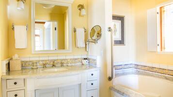 A bathroom with a large mirror, two sinks, a bathtub, and a toilet.