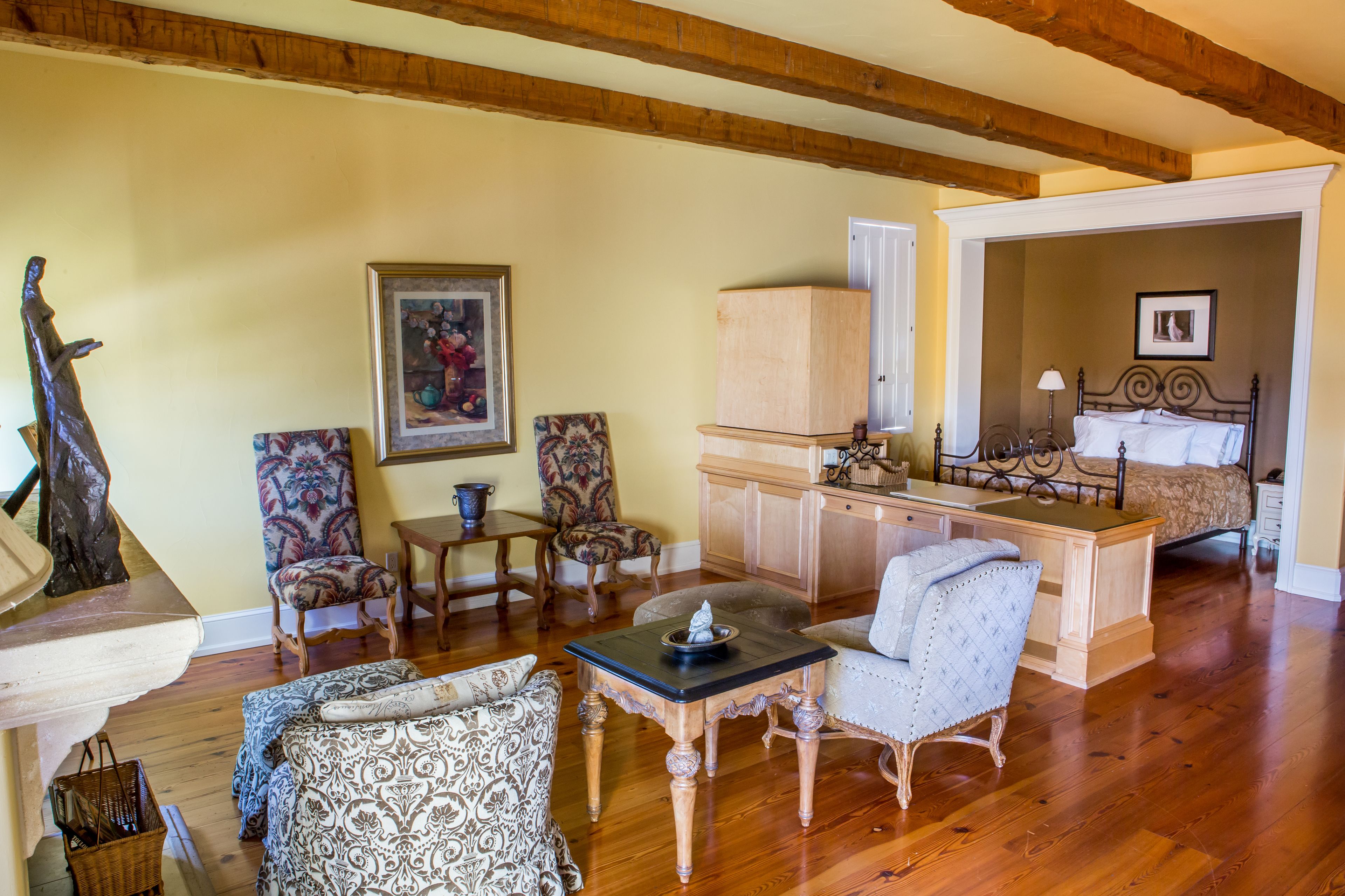 Amplia sala de estar con piso de madera, comedor y un dormitorio con cama y mesita de noche.