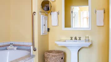A bathroom with a bathtub, a sink, a mirror, and a handrail.