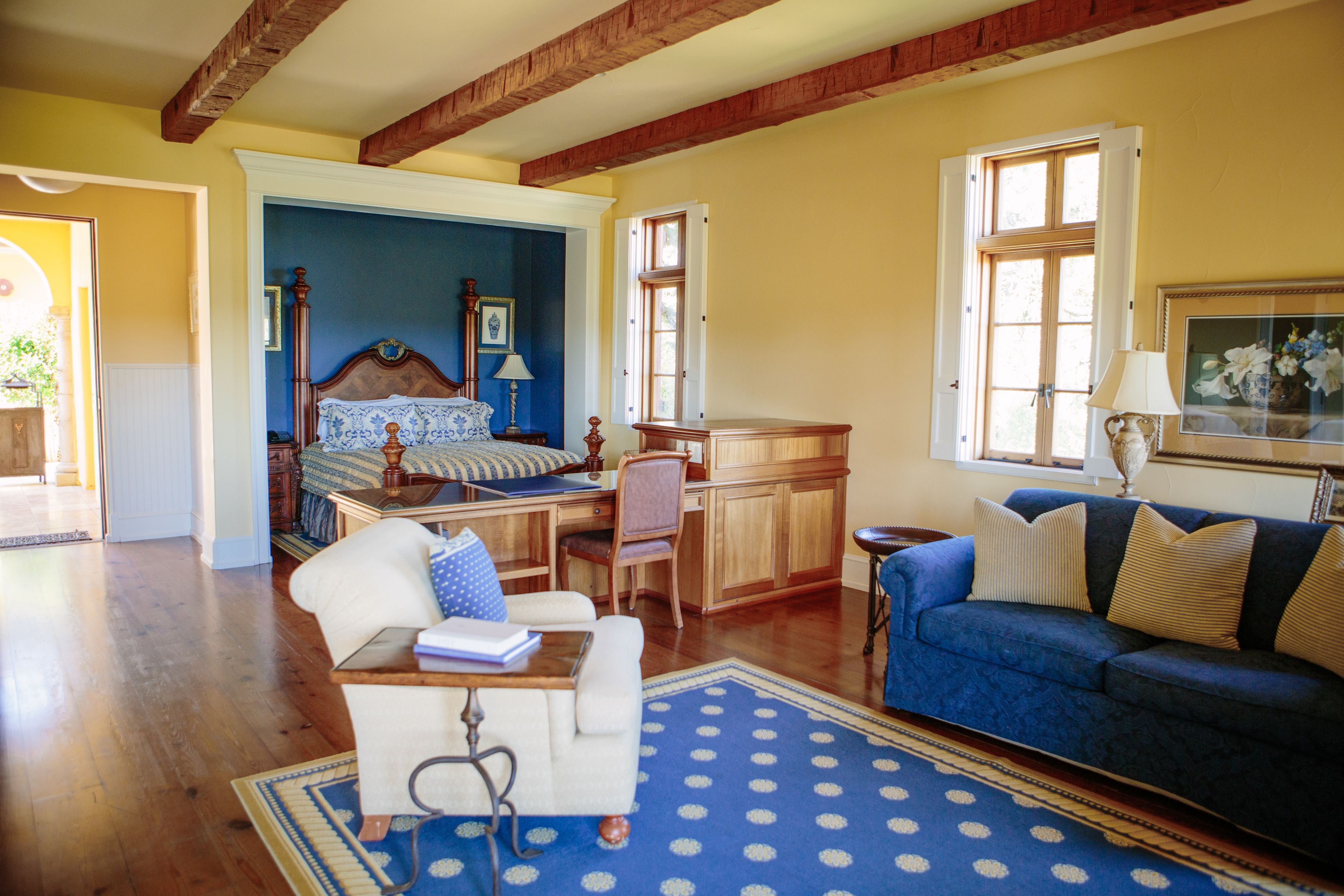 Un salón amplio con un sofá azul, una mesa de centro de madera y una alfombra azul estampada.