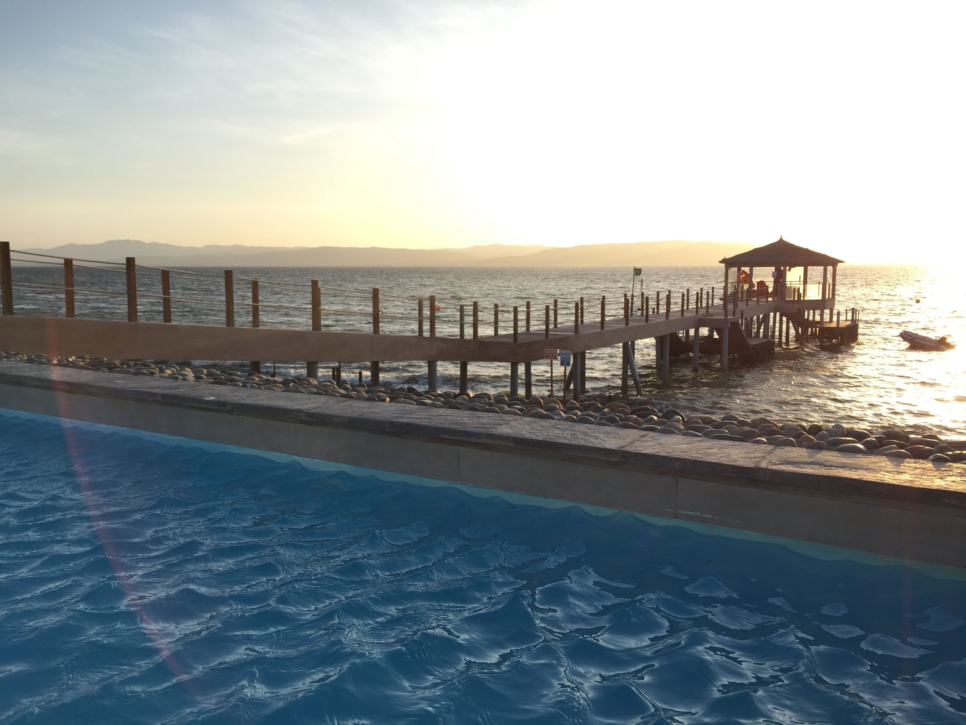 A pier extending into the water with a gazebo at the end, overlooking a body of water with a distant shoreline.