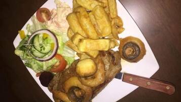 Une assiette avec un filet de poisson, des frites et une salade.