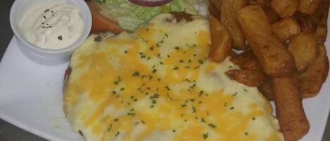 A plate with a sandwich, fries, salad, and a small bowl of sauce.