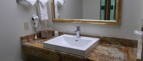 A bathroom with a white sink, a mirror, and a hairdryer on the wall.