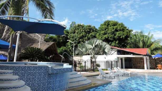 Un área de piscina con escalones de cerámica, sillas de descanso y sombrillas.
