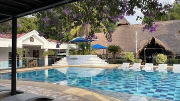 Una piscina al aire libre, sillones reclinables de piscina