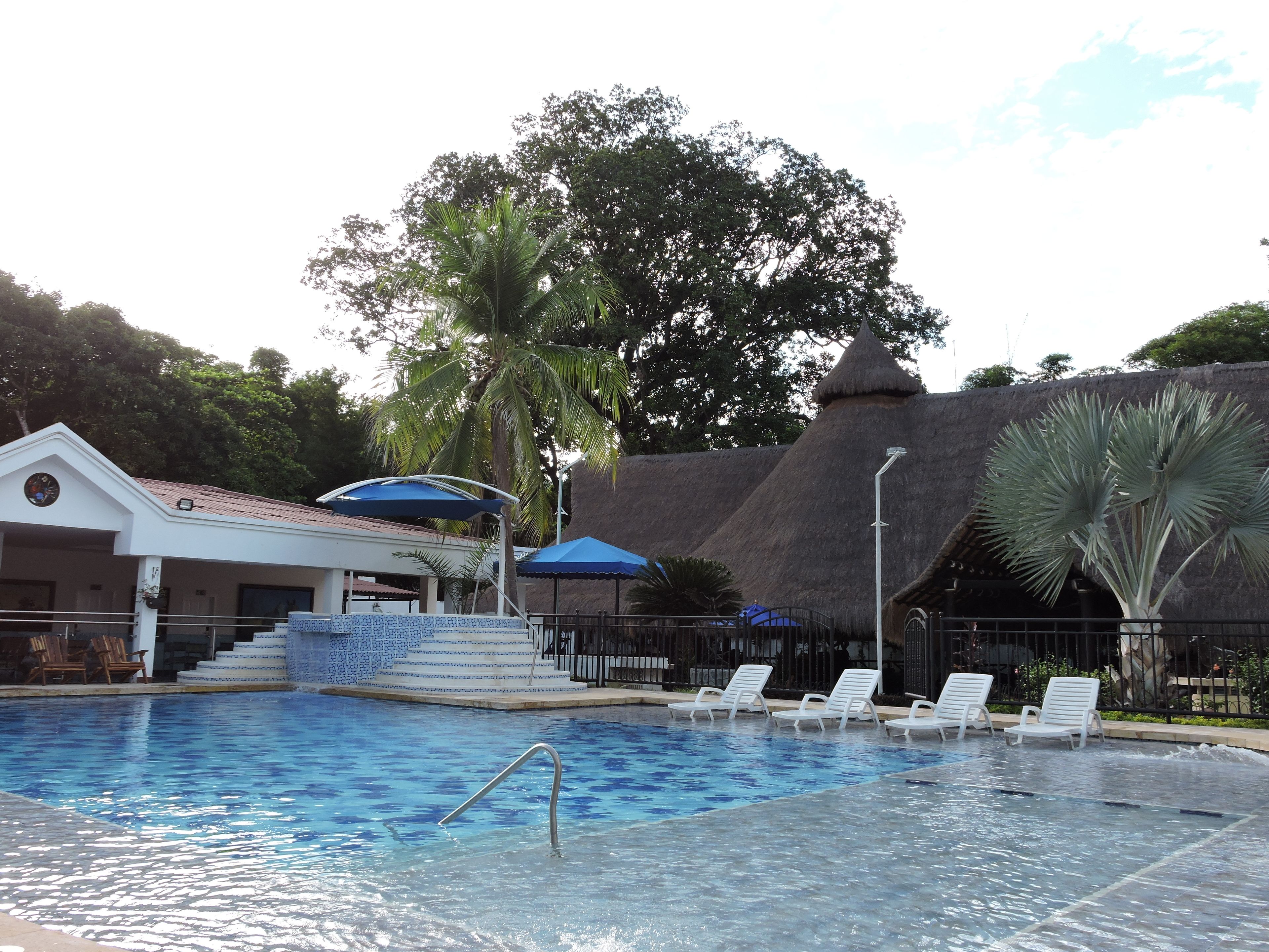 Piscina con sillas de descanso y un área de estar techada.