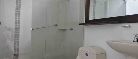 Un baño con cabina de ducha de vidrio, inodoro y lavabo.