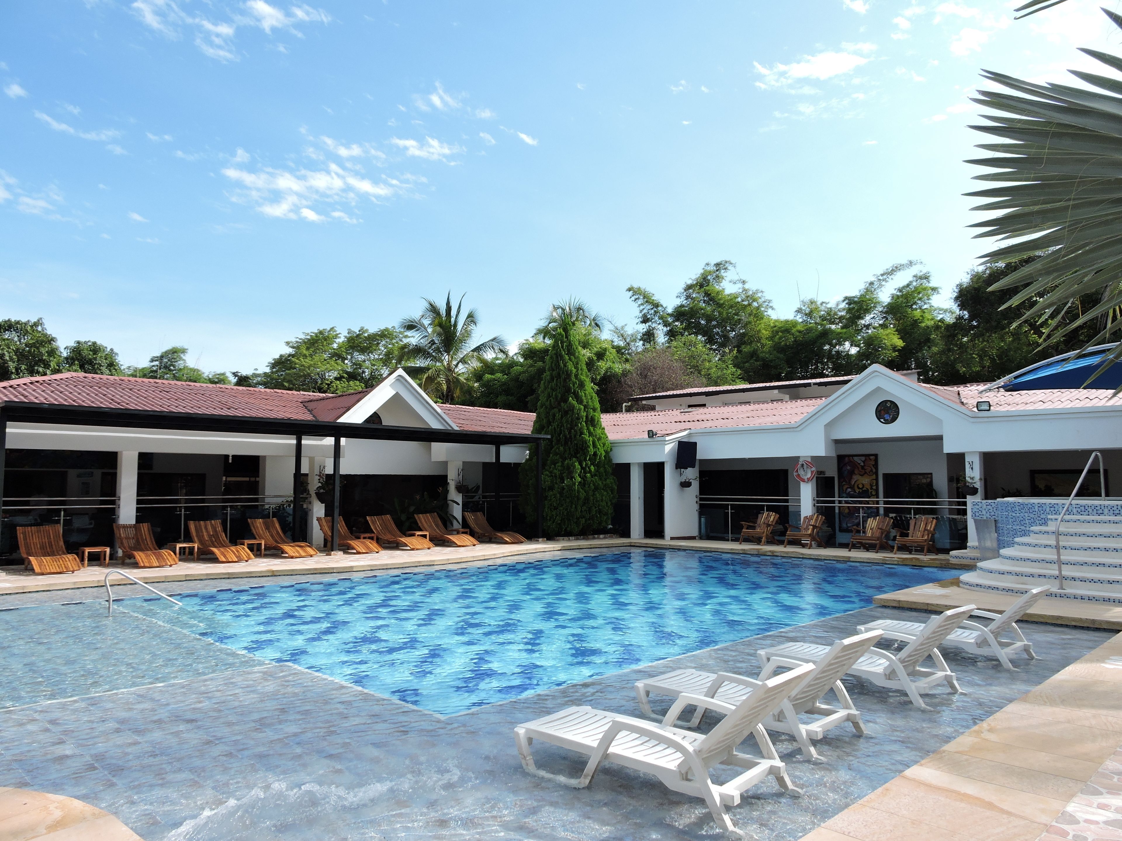 Una piscina al aire libre, sillones reclinables de piscina