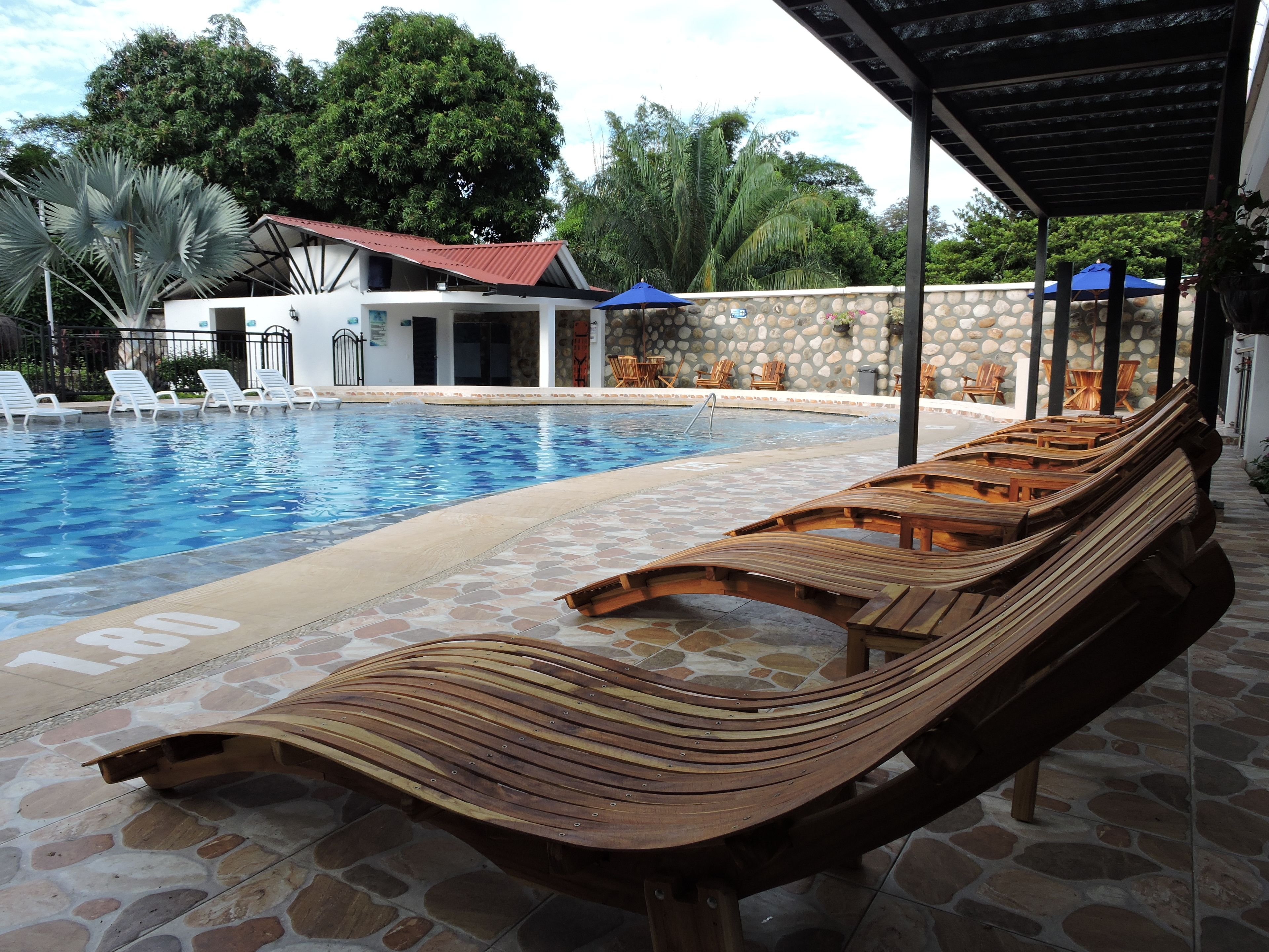 A pool area with lounge chairs and a covered seating area.